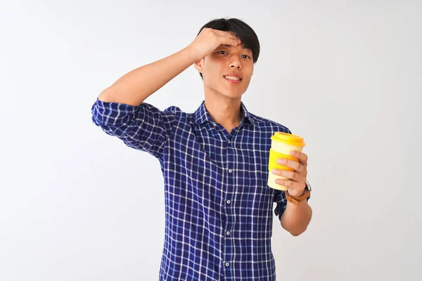 Young chinese man drinking take away coffee standing over isolated white background stressed with hand on head, shocked with shame and surprise face, angry and frustrated. Fear and upset for mistake.
