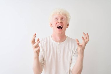 Genç albino sarışın adam rahat t-shirt izole beyaz arka plan deli ve deli bağırarak ve agresif ifade ve kollar kaldırdı ile bağırıyor üzerinde duran giyiyor. Hayal kırıklığı kavramı.