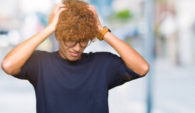 Yakışıklı genç afro gözlük çünkü umutsuz ve stresli baş ağrısı acı acı ve migren ile. Ellerini kafasına.