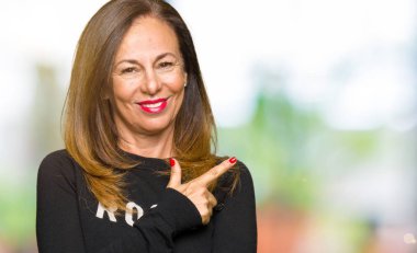 Yüzüne mutlu ve doğal ifade ile yan kadar el ve parmak ile işaret yüz bir gülümseme ile neşeli rock ve rulo kazak giyen güzel orta yaş kadın