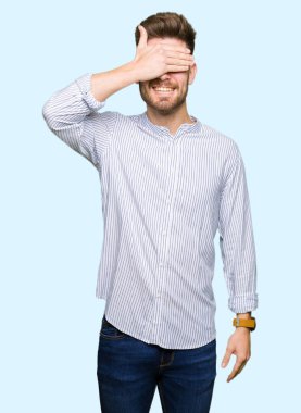 Gülümseyen ve gülen genç yakışıklı adam şaşırmak için gözlerini kapatıyor. Kör kavram.