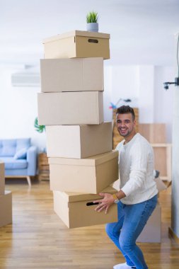 Genç yakışıklı adam yeni bir daireye hareket, karton kutular bir yığın tutan, yeni ev için mutlu