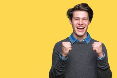 İzole arka plan üzerinde genç yakışıklı zarif adam şaşırttı ve silah kaldırdı ve açık gözleri ile başarı için hayran kutluyor. Kazanan kavramı.