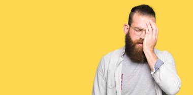 Yarım yüz, göz ve ağız el ile kapsayan yorgun esneme gözlüklü genç sarışın adam. Acı yüzü acıyor.