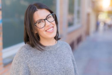 Genç güzel kadın gözlük giyerek şehir kasabasında sokakta emin yürüyüş gülümsüyor