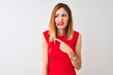 İzole beyaz arka plan üzerinde duran zarif kırmızı elbise giyen Redhead iş kadını işaret parmağı ile endişeli ve sinirli bir kenara işaret parmağı, endişeli ve sürpriz ifade