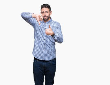 Yakışıklı delikanlı izole arka plan yapmaya başparmak yukarı ve aşağı, anlaşmazlık ve anlaşma ifade üzerinde. Deli çatışma