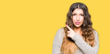 Kış lık elbise giyen genç güzel kadın yan yana el parmağıyla işaret reklam gösteren, ciddi ve sakin bir yüz