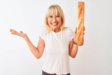 Orta yaş fırıncı kadın izole beyaz arka plan üzerinde duran ekmek tutan çok mutlu ve heyecanlı, kazanan ifade büyük bir gülümseme ile çığlık zafer kutluyor ve ellerini kaldırdı