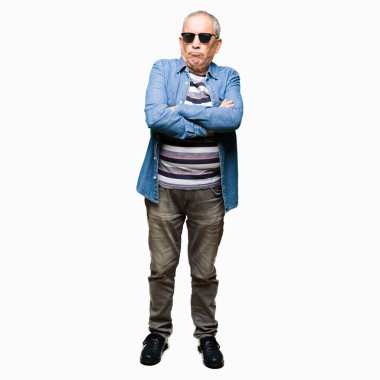 Kot ceket ve güneş gözlüğü, şüpheci ve sinir giyen yakışıklı kıdemli adam, kesişmiş kollar ile yüzünde onaylamayan ifade. Negatif kişi.