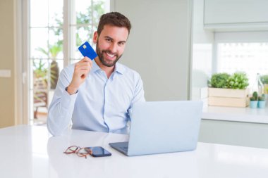 Yakışıklı iş adamı alışveriş online bilgisayar dizüstü kullanarak ve 