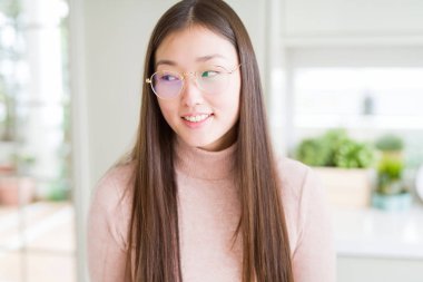 Gözlüklü görünümlü yan ve dik dik bakma uzağa düşünce gülümseyen güzel Asyalı kadın.