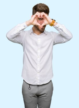 Genç yakışıklı iş adamı yapıyor kalp şekli ile el ve parmak işareti seyir gülümseyen