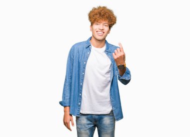 Afro saçlı kot ceket giyen genç yakışıklı adam Beckoning gel burada mutlu ve gülümseyerek el davet ile jest