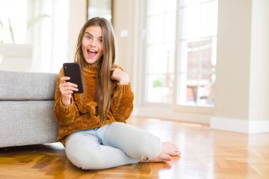 Güzel genç kız çocuk kendisi için sürpriz yüz işaret parmağı ile Smartphone kullanarak ileti gönderme