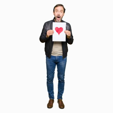 Kırmızı kalp şok sürpriz yüzü, korkuyor ve korku ifadesi ile heyecanlı olan korkmuş ile kağıt tutan yakışıklı orta yaş erkek