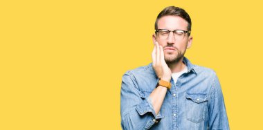 Yakışıklı adam diş ağrısı veya diş üzerinde diş hastalığı nedeniyle ağrılı ifade ile el ile ağız dokunmadan gözlük takan. Diş hekimi konsepti.