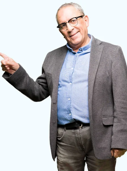 Yüzünde, kocaman bir gülümseme ile gözlük takan yakışıklı üst düzey businesss adam kameraya bakarak yan el ve parmak ile işaret.