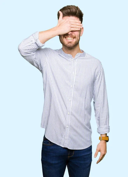 Gülümseyen ve gülen genç yakışıklı adam şaşırmak için gözlerini kapatıyor. Kör kavram.