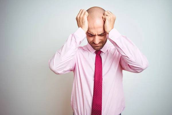Young business man wearing pink tie over isolated background suffering from headache desperate and stressed because pain and migraine. Hands on head.