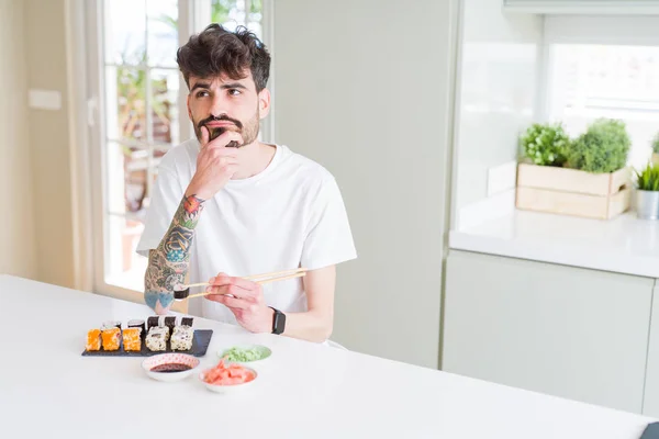 Joven Comiendo Sushi Asiático Entrega Domicilio Cara Seria Pensando Pregunta — Foto de Stock