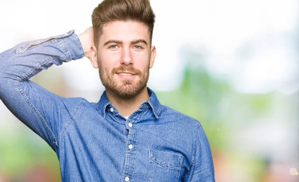 Genç yakışıklı sarışın adam rahat kot gömlek giymiş yanıltır ve soru hakkında merak ediyorum. Şüphe, kafasına el ile düşünme ile belirsiz. Dalgın kavramı.