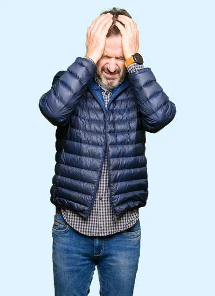 Orta yaş yakışıklı adam giyen kış ceket çünkü umutsuz ve stresli baş ağrısı acı acı ve migren. Ellerini kafasına.