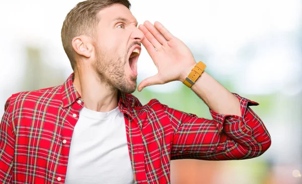 Handsome man wearing casual shirt shouting and screaming loud to side with hand on mouth. Communication concept.