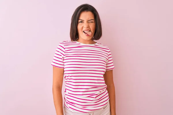 年轻的美女穿着条纹T恤站在孤立的粉红色背景坚持舌头与有趣的表情高兴 情感概念 — 图库照片