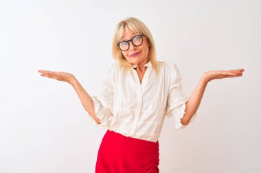 Orta yaş iş kadını gömlek ve gözlük giyen izole beyaz arka plan üzerinde duran habersiz ve kolları ve elleri ile karışık ifade kaldırdı. Şüphe kavramı.