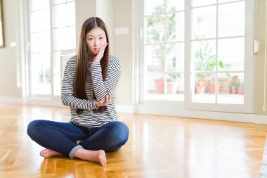 Güzel Asyalı kadın evde yalınayak oturan yorgun görünümlü ve çapraz kolları ile depresyon sorunları ile sıkılmış düşünme.