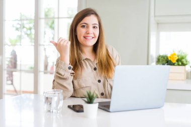 Güzel genç kadın bilgisayar dizüstü kullanarak işaret ve mutlu yüzü gülümseyerek yan başparmak ile gösteren