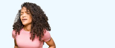 Kıvırcık saçlı Genç güzel kadın, mide üzerine el ile pembe t-shirt giyiyor çünkü hazımsızlık, ağrılı hastalık rahatsızlık hissi. Ağrı kavramı.