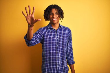 Dreadlocks rahat gömlek giyen Afro adam izole sarı arka plan üzerinde duran gösteren ve emin ve mutlu gülümserken parmakları sayısı beş işaret.