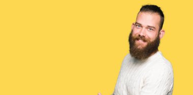 Kış kazak giyen genç hipster adam açık el ile gülümseyen doğal girmek için davet