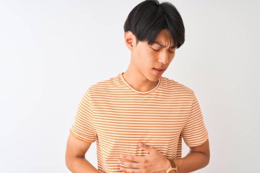 Genç Çinli adam rahat çizgili t-shirt mide üzerinde el ile izole beyaz arka plan üzerinde duran giyen çünkü hazımsızlık, ağrılı hastalık duygusu. Ağrı kavramı.