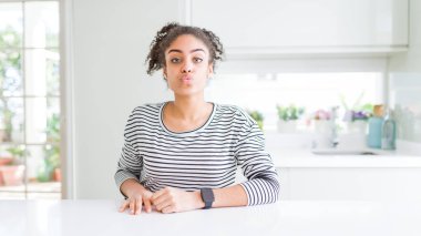 Afro saçlı güzel afro-amerikan kadın rahat çizgili kazak giyen kamera hava güzel ve seksi olmak bir öpücük üfleme bakarak. Aşk ifadesi.