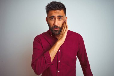 Genç hintli adam gizli söylenti anlatan ağız üzerinde izole gri arka plan el üzerinde duran kırmızı zarif gömlek giyen, kötü niyetli konuşma konuşma fısıldıyor