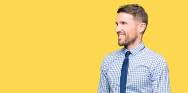 Yakışıklı iş adamı kravat giyen yüzünde gülümseme, doğal ifade ile yan bakıyor. Gülmekten emin.