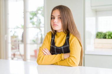 Genç güzel sarışın çocuk kız evde rahat sarı kazak giyen şüpheci ve sinirli, çapraz kolları ile yüzünde onaylamayan ifade. Negatif kişi.