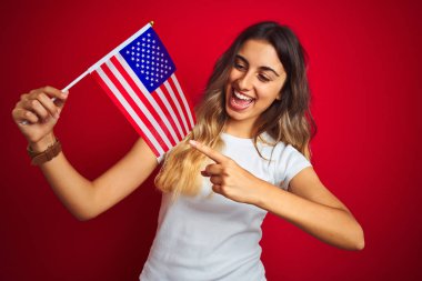Kırmızı izole arka plan üzerinde Amerika bayrağı tutan genç kadın el ve parmak ile işaret çok mutlu