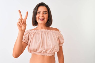 Genç güzel kadın rahat t-shirt izole beyaz arka plan üzerinde duran gösteren ve parmakları ile işaret ederken emin ve mutlu gülümseyerek iki numara.