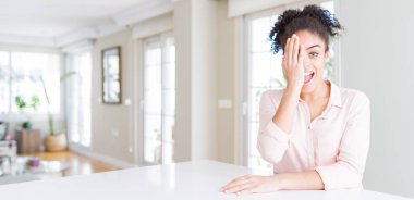 Afro saçlı, bir gözünü eliyle kaplayan, yüzünde kendine güvenen gülümseme ve sürpriz duygu ile güzel afro-amerikan kadın geniş açı.