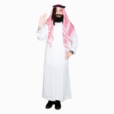 Arap iş adamı geleneksel keffiyeh giymiş uzun saçlı Waiving selam söyleyerek mutlu ve gülümseyerek eşarp, dostça jest hoş geldiniz