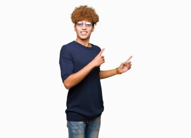 Afro gülümseyen ve iki elleri ve parmakları ile tarafına işaret kamera bakarak gözlüklü genç yakışıklı adamla.