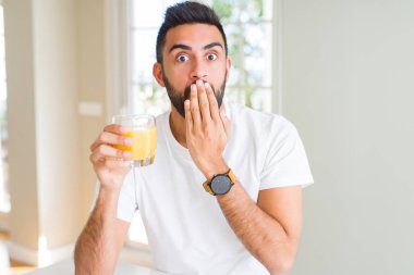 Yakışıklı İspanyol adam hata için utanç ile şok el ile sağlıklı portakal suyu kapağı ağız içme, korku ifadesi, sessizlik, gizli kavram korkmuş