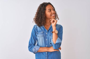 Denim gömlek giyen genç Brezilyalı kadın elini çeneüzerinde düşünerek izole beyaz arka plan üzerinde duran soru, dalgın ifade. Gülümseyen ve düşünceli bir yüz. Şüphe kavramı.