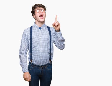 Mavi t-shirt üzerinde izole giyen genç yakışıklı adam arka plan bir parmak, harika bir fikir ya da düşünce, iyi hafıza ile baş gösteren gülen