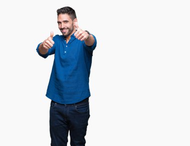 Yakışıklı delikanlı el ile pozitif jest yapıyor onaylama izole arka plan üzerinde başparmak gülümseyen ve başarı için mutlu. Kamera, kazanan jest arıyorsunuz.