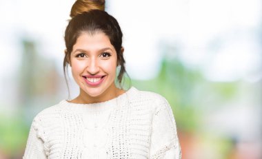 Yüzünde mutlu ve havalı bir gülümseme olan kışlık süveter giyen genç ve güzel bir kadın. şanslı kişi.